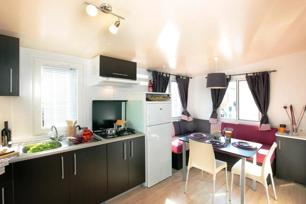 a kitchen with a table and a small kitchen with a table and chairs at Sottomarina Bungalows Spiaggia in Sottomarina