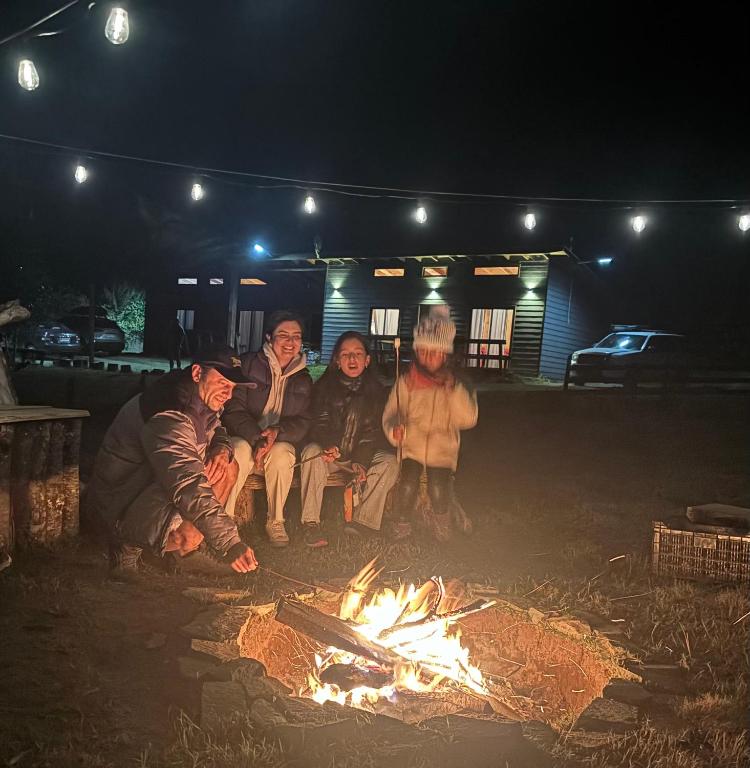 a group of people sitting around a fire at Cabañas Troncos de Relin in Panguipulli
