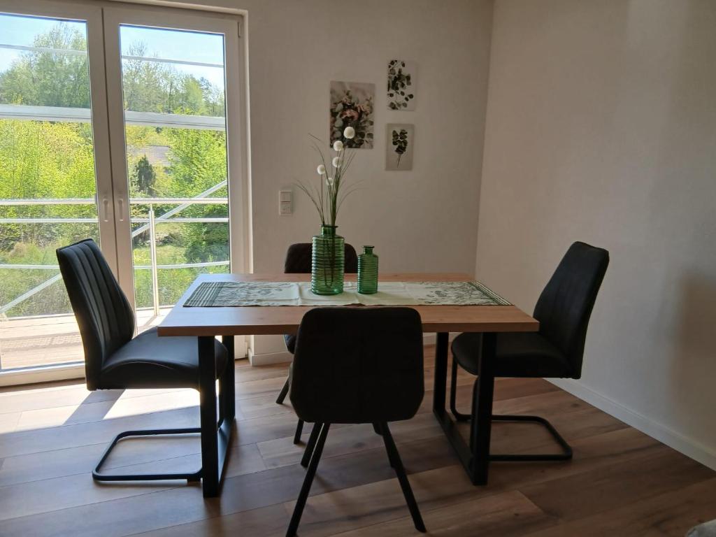 a dining room table with chairs and a vase with flowers at Ferienwohnung Sägmühlweiher in Ludwigswinkel