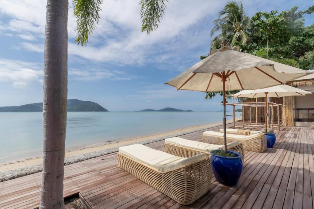 a wooden deck with chairs and an umbrella on the beach at NEW Serenity Tropical 2 Bed Condo On Beachfront in Ban Saiyuan (1)