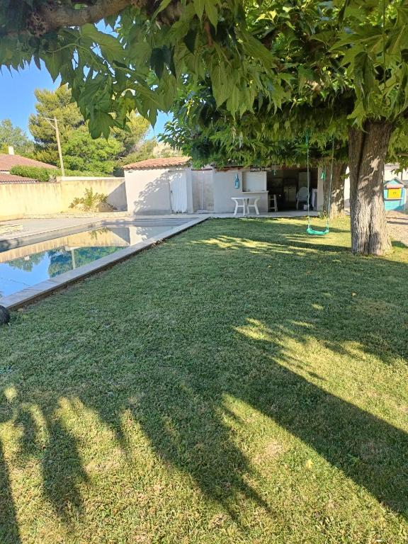 a yard with a tree and a swimming pool at Chambre des Iris in Graveson