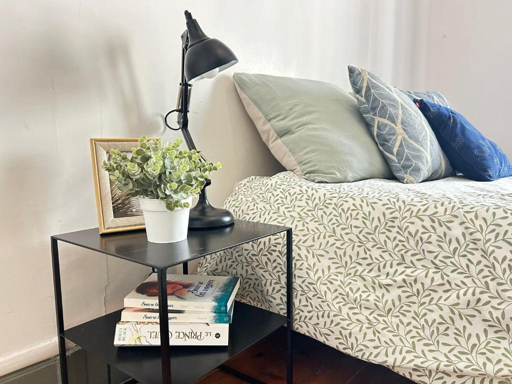 a lamp on a table next to a bed with pillows at Cosy Magnolia Quartz - T3 - Hyper centre avec Parking in Pau
