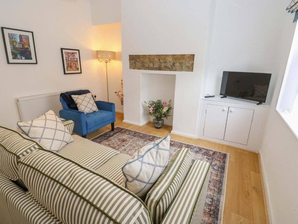 a living room with a couch and a tv at Saltaire House in Saltaire