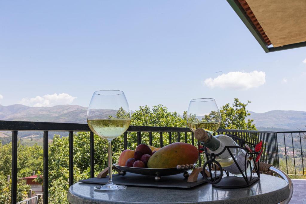 a table with two glasses of wine and a basket of fruit at Casa de Jonathan in Vilarinho do Souto