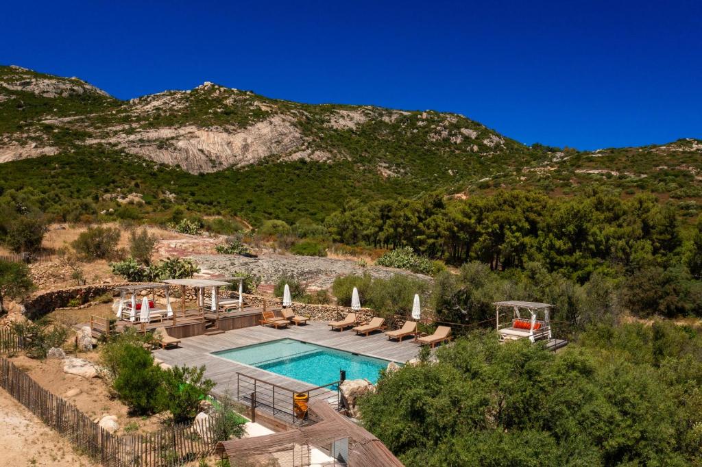 a swimming pool with chairs and a mountain at Villa Les Bergeries De Calvi in Calvi