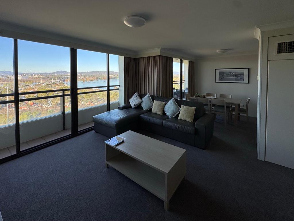 a living room with a couch and a table at Lakefront Panorama – Sky Collection Suite in Canberra