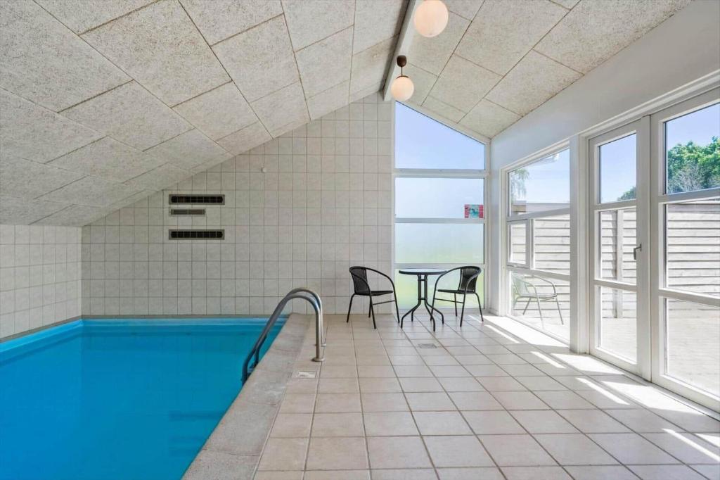 a swimming pool in a room with a table and chairs at M300-Vaeggerlose-Stolt-Henriksvej-53 in Bøtø By