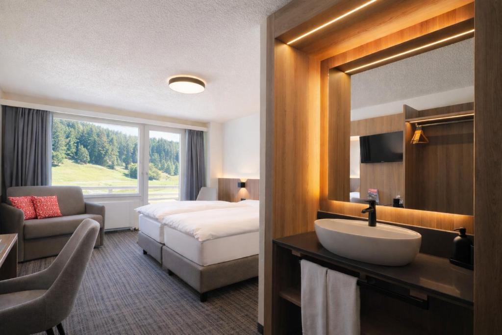 a hotel room with a bed and a sink at Hotel Alpina Parpan in Parpan