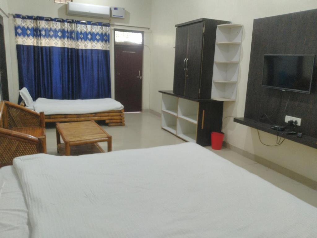 a bedroom with a bed and a tv and a couch at Natraj hotel rooms and restaurant in Motīnāla