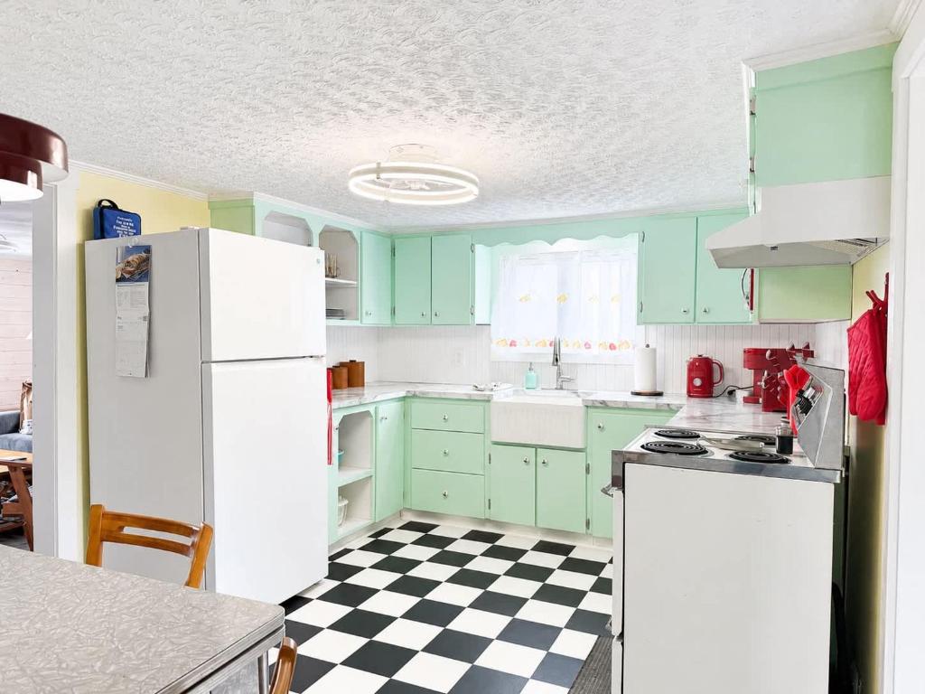 a kitchen with green cabinets and a black and white checkered floor at Whimsea Cottage in Twillingate