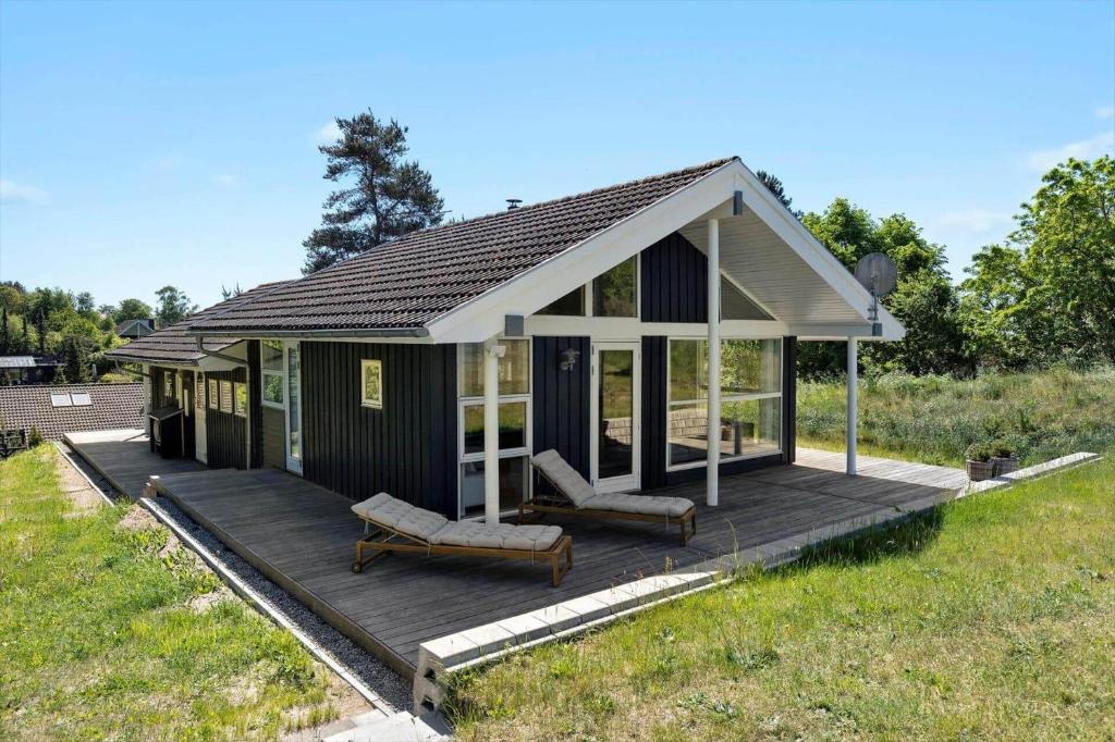 a small house with a deck in a field at 84174-Knebel-Fuglsovig-301 in Knebel