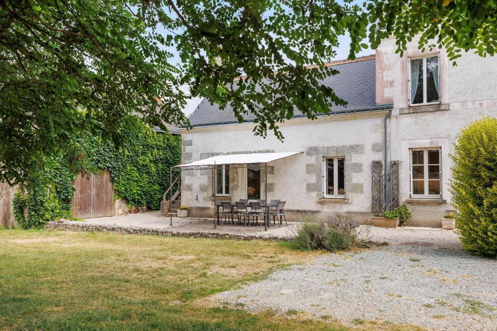 a house with a table and chairs in the yard at Le Café de l'Encloître in Beaumont-la-Ronce