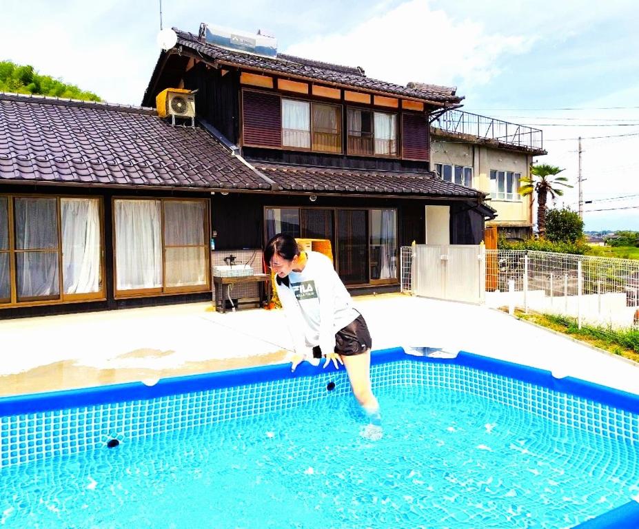 a woman standing in the water in a swimming pool at とっくりhouse in Takashima