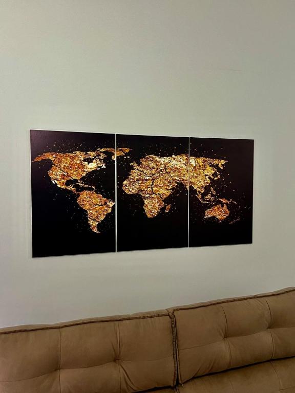 four paintings of the world on a wall above a couch at Apartamento Icônico em Petrópolis in Petrópolis