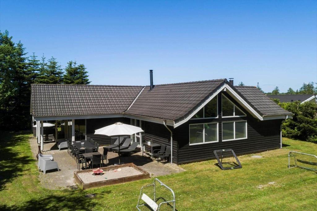 a black house with a picnic table and umbrella at M191-Vaeggerlose-Baeverstien-46 in Bøtø By