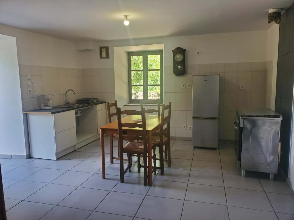 a kitchen with a table and chairs and a refrigerator at Studio Beau rêve in Le Cheylard