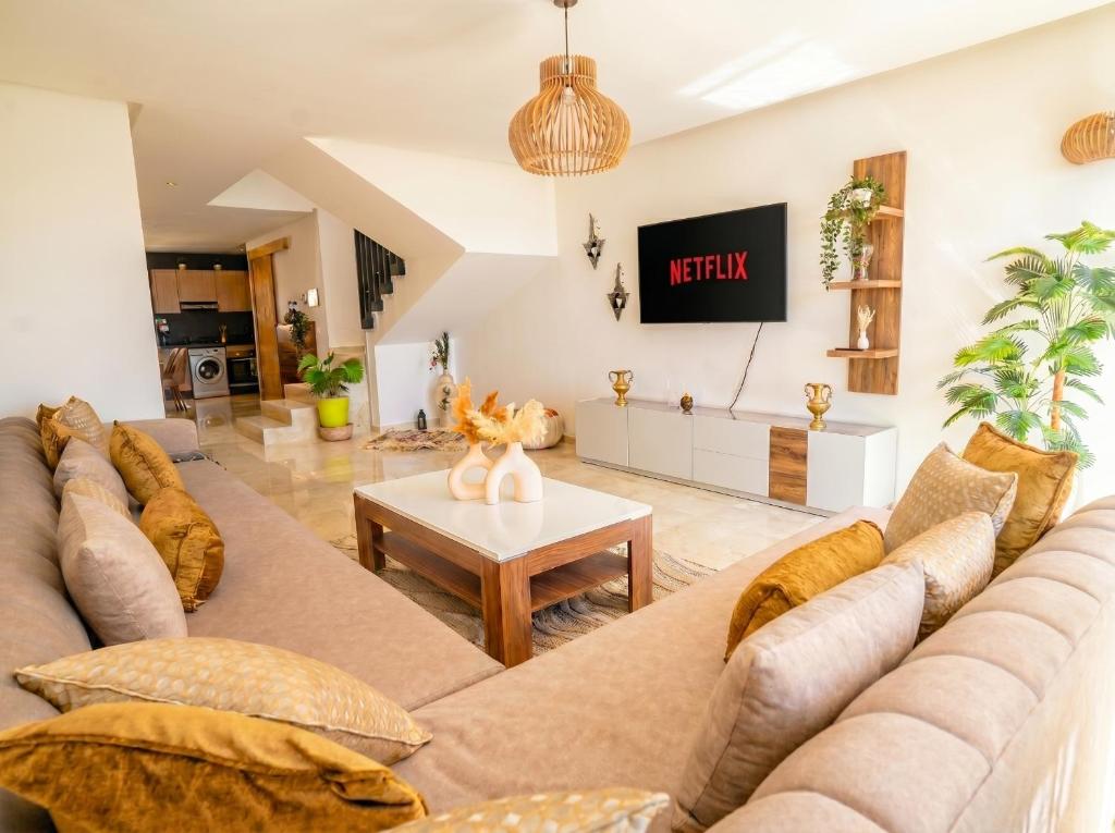 a living room with a large couch and a table at Ocean View Duplex & Golf, Taghazout Bay in Tamraght Ouzdar
