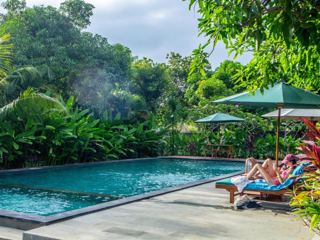 a woman laying in a chair next to a swimming pool at Griyani Homestay in Uluwatu