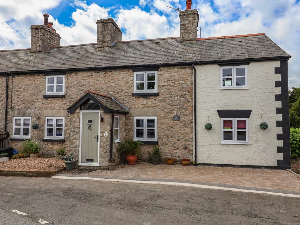 a brick house with a white door at Tenandeleven Cottage in Denbigh