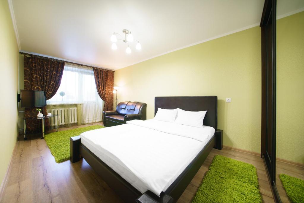 a bedroom with a large white bed and a chair at PaulMarie Apartments on Oktyabrskaya in Bobruisk