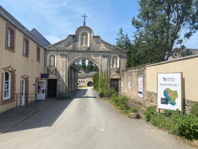 an old church with an archway in a street at Hôtellerie Abbaye Port du Salut in Entrammes