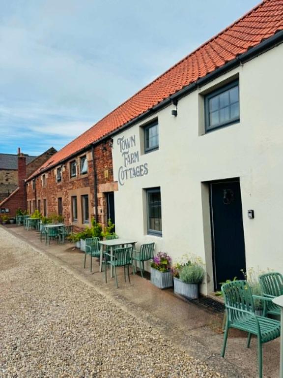 a row of tables and chairs in front of a building at Town Farm Cottages Beadnell by Coast & Country Stays in Beadnell