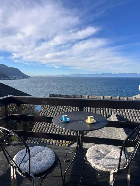 a table and chairs on a balcony with the ocean at Between Mountain and Sea in Cape Town