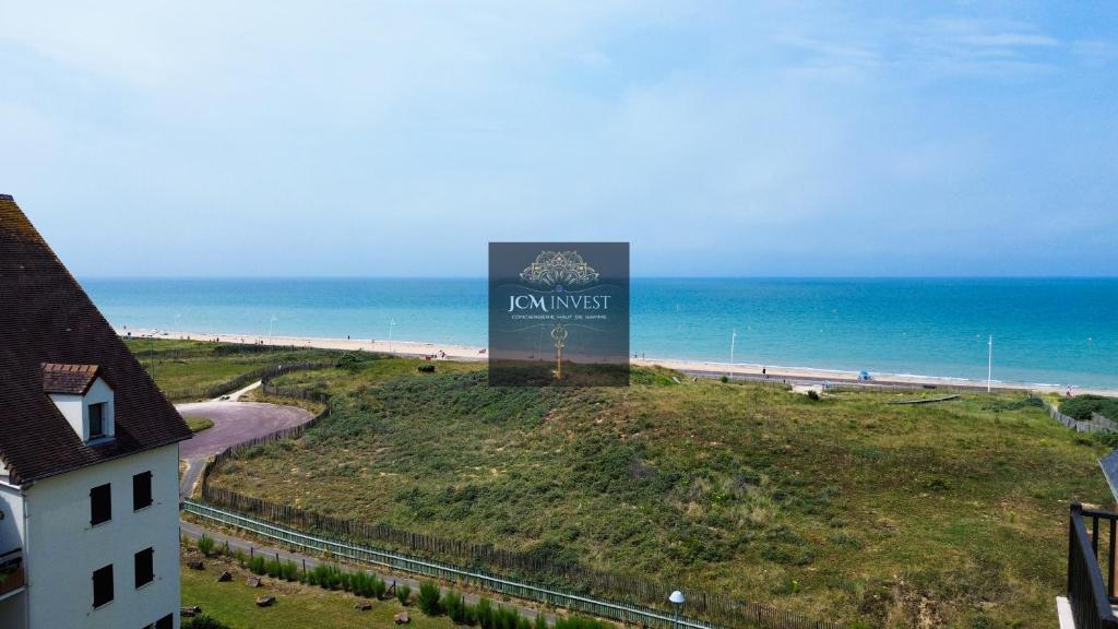 a sign on a hill next to the beach at Duplex vue mer, balcon, parking privé in Cabourg