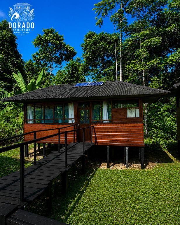 a small house with a deck in the grass at Dorado Lodge in Manú