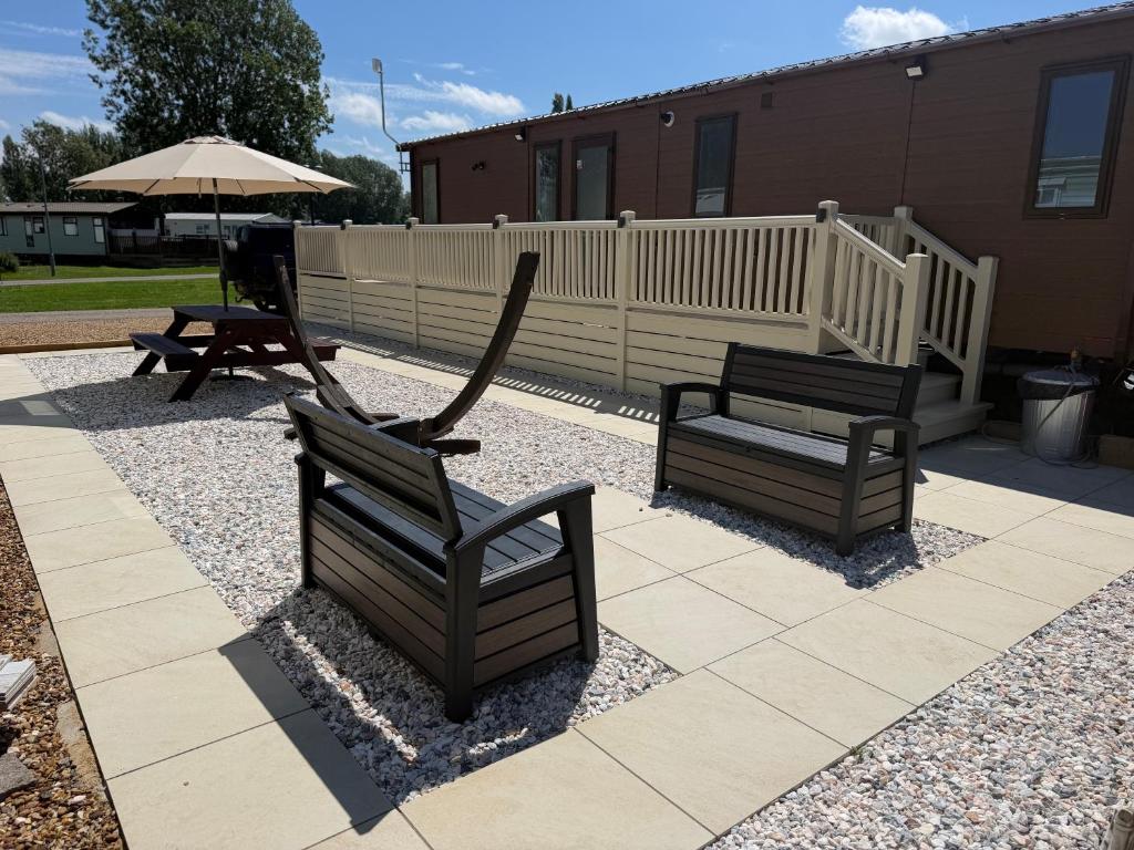 two benches and an umbrella on a patio at S&K Lodge Billing Aquadrome Holiday Park, Great billing ,Northampton , NN3 9DA in Northampton