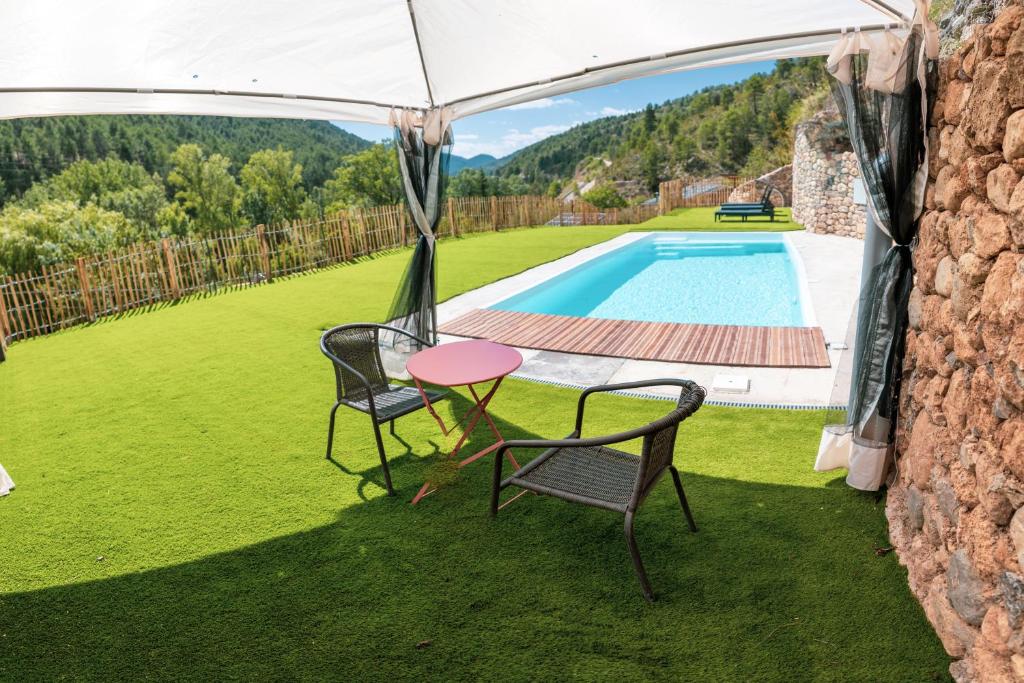 a table and chairs under a tent next to a swimming pool at Casa Rural Molí de Fòrnols in Fornols