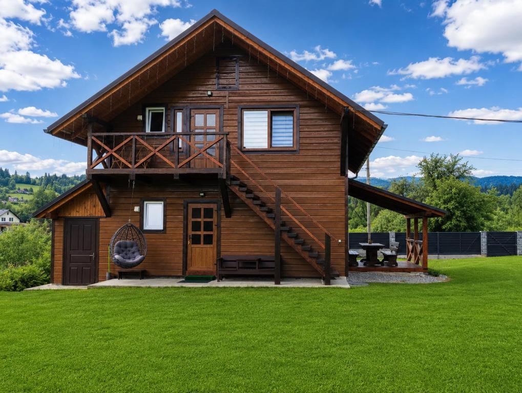 a log cabin with a deck on a lawn at Гостинний двір in Vorokhta