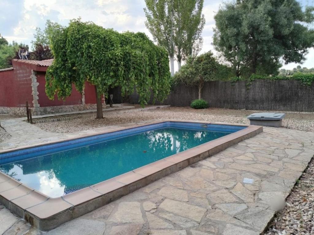 a swimming pool in a yard with a stone patio at Casa Rural en El Burguillo - Puerto Pez in Las Cruceras