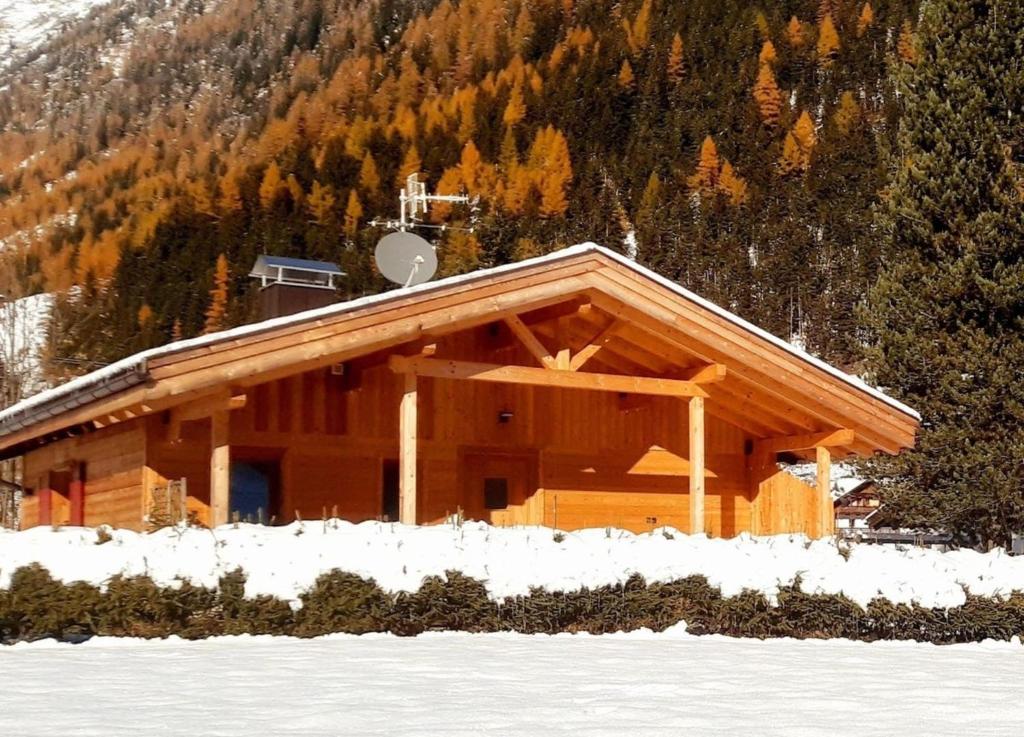 a log cabin in the snow in front of a mountain at Ausserhof Hütte mit Sauna Südtirol in Riobianco