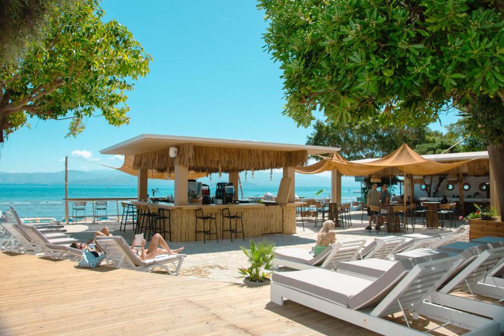 a group of people sitting in lounge chairs on the beach at Newquay beach club in Kavos