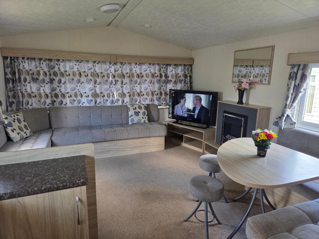 a living room with a couch and a tv at Awesome Static Caravan Holiday Home in Great Billing