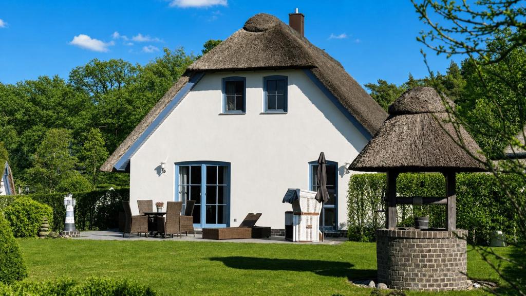 a cottage with a thatched roof and a gazebo at Ferienhaus Strandperle in Loddin