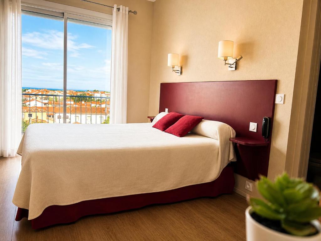 a bedroom with a large bed with a large window at Hôtel Saint Jacques in Sorède