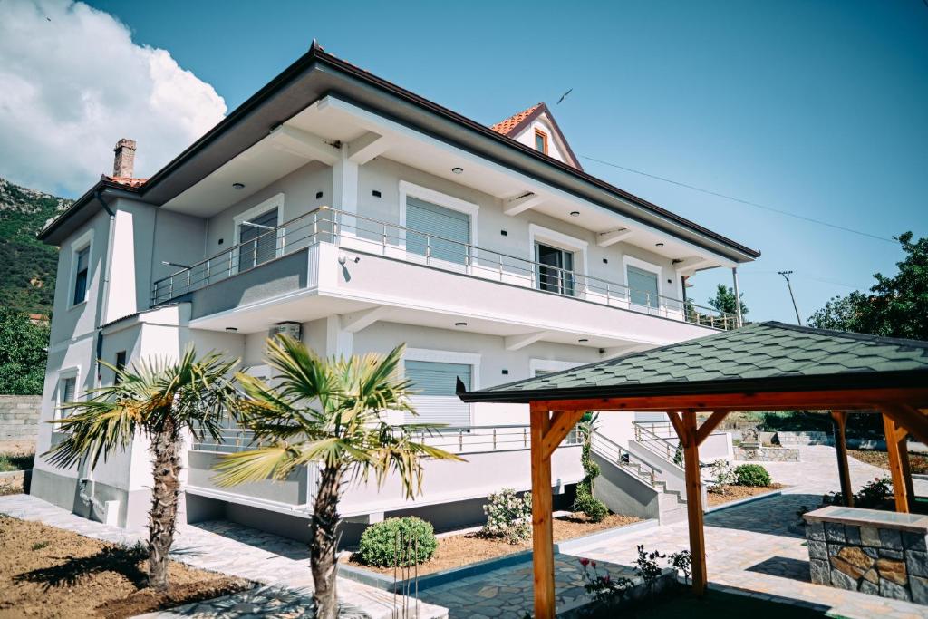 a white house with a balcony and palm trees at Vila BENE in Pogradec