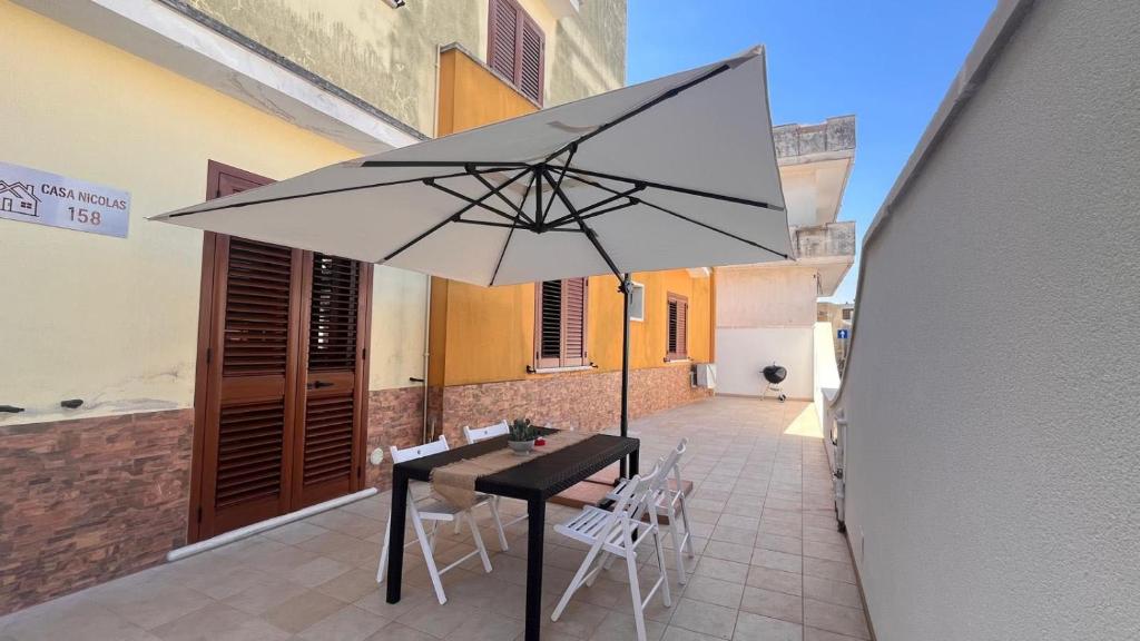 a black table with a white umbrella on a patio at CASA NICOLAS 158 by SalentoAffitti in Neviano