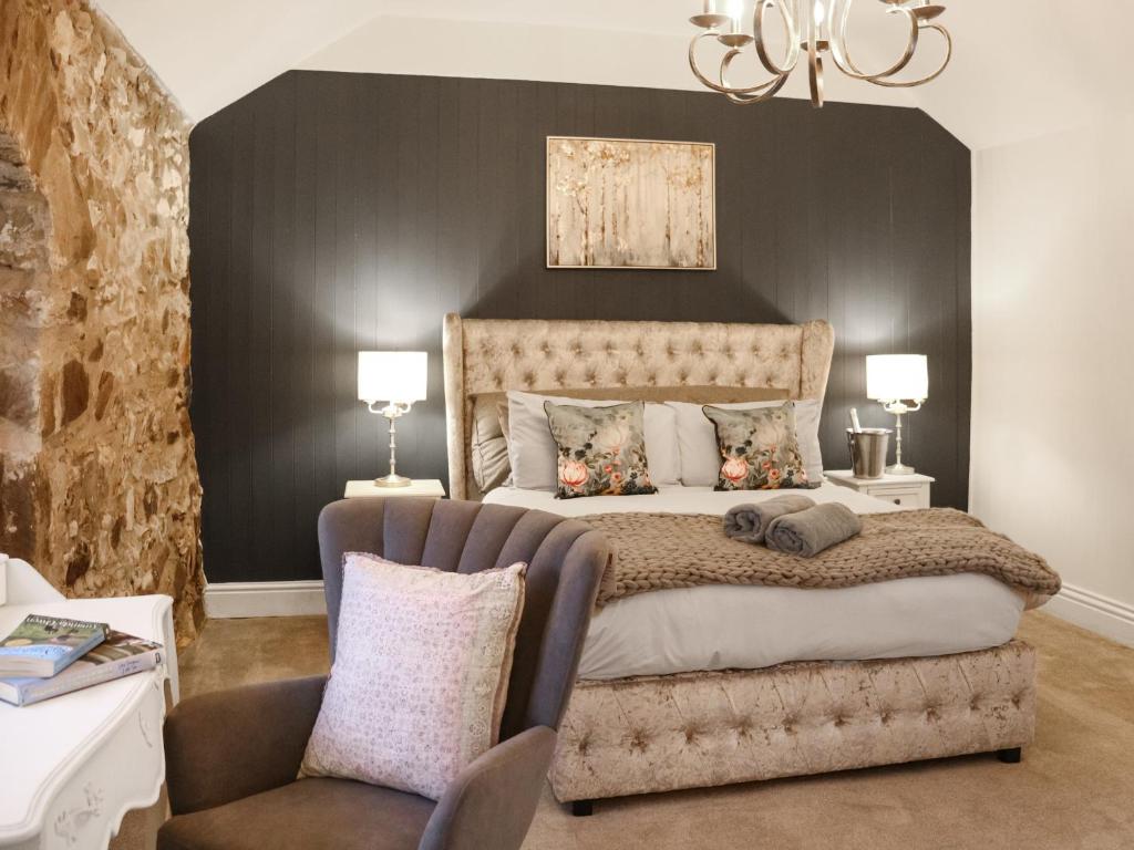 a bedroom with a large bed and a chair at Stable End in Llandysul
