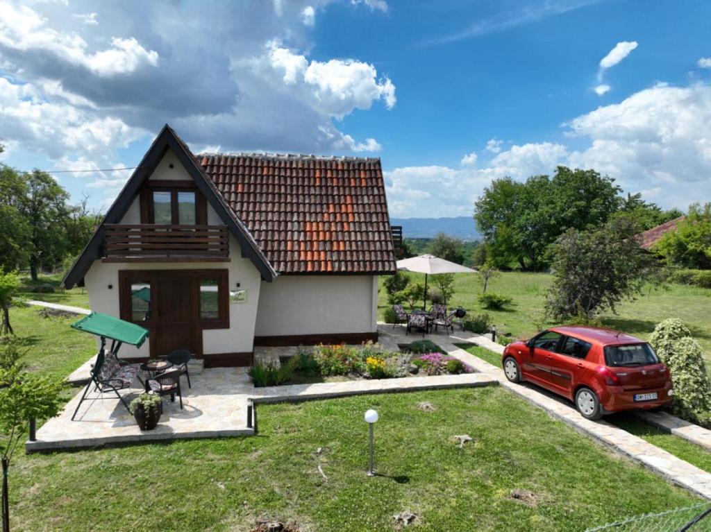 a small house with a red car parked in the yard at Kiki house in Čačak