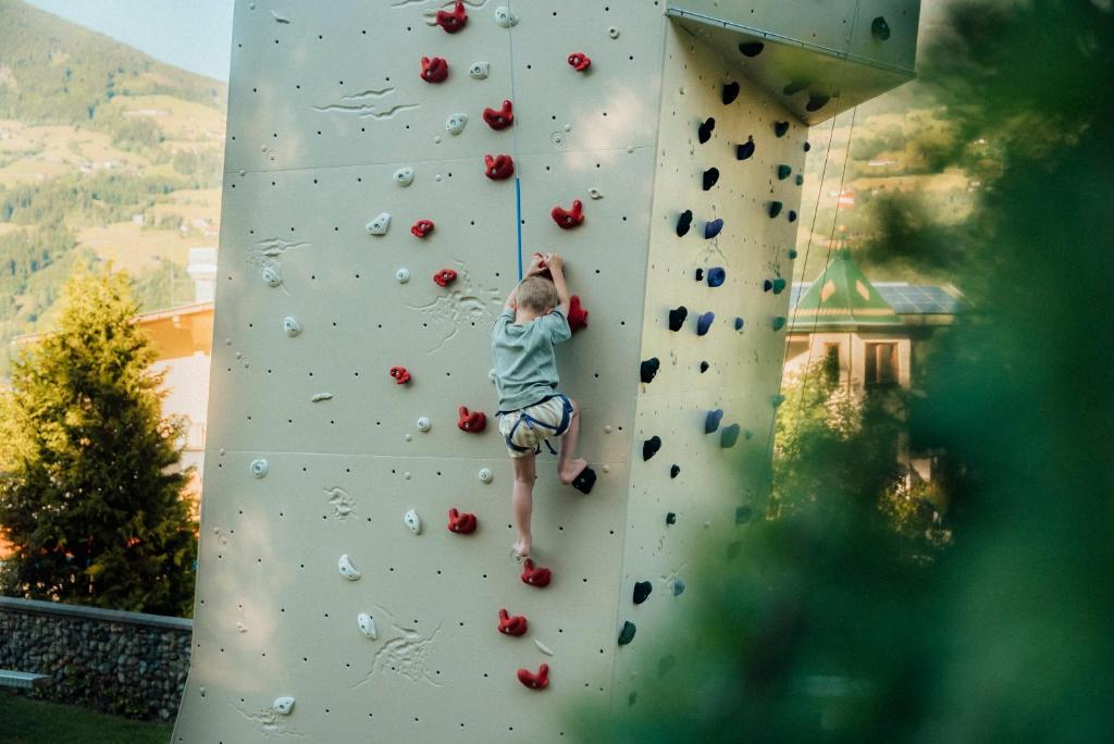 a young boy is climbing a climbing wall at Alpin Family Resort Seetal in Kaltenbach