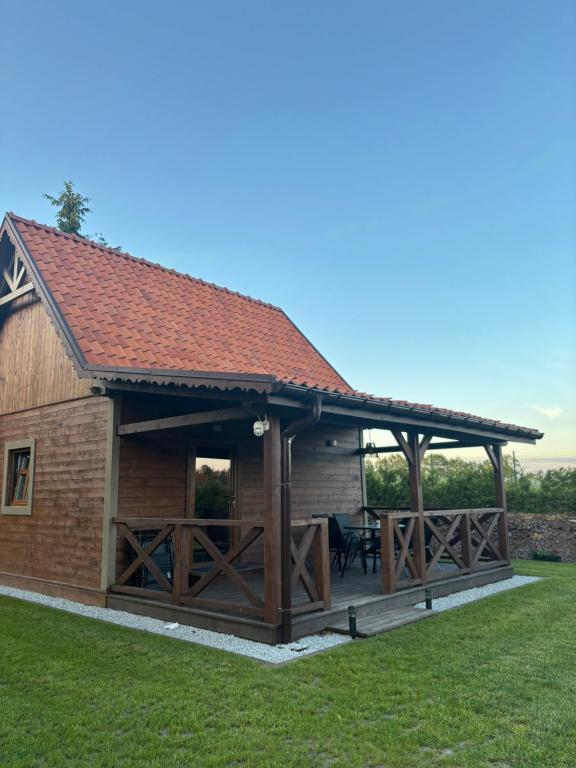 a large wooden pavilion with a deck in the grass at Domki Stokrotka in Ruciane-Nida