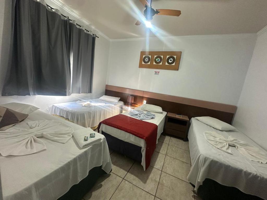 a hotel room with three beds and a ceiling at Hotel Ype de São Carlos in São Carlos