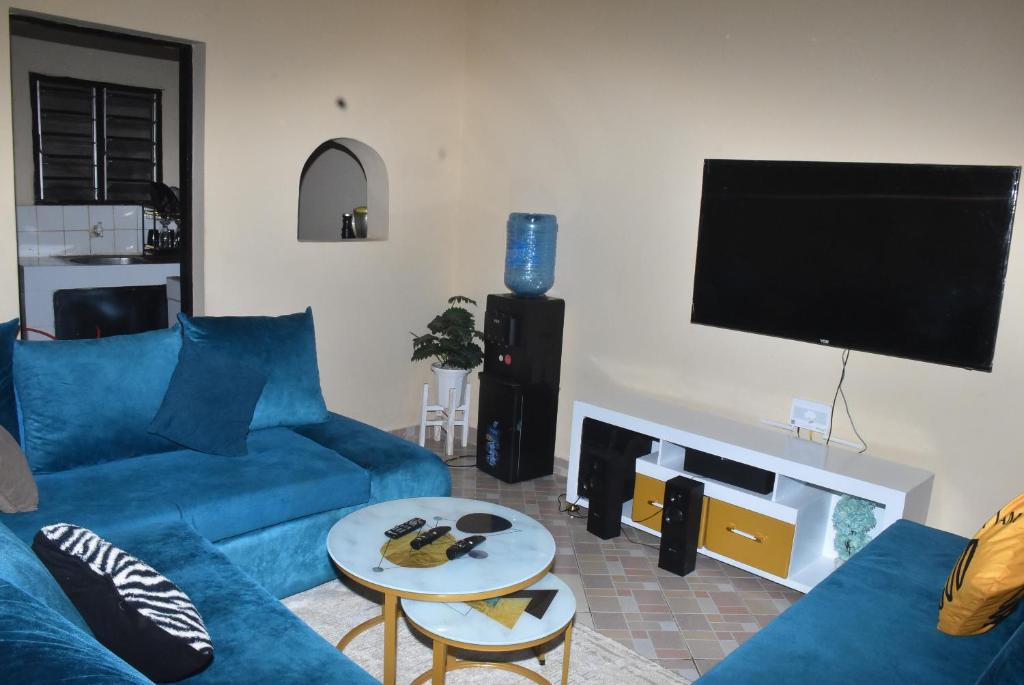 a living room with a blue couch and a flat screen tv at Maya Haven in Ukunda