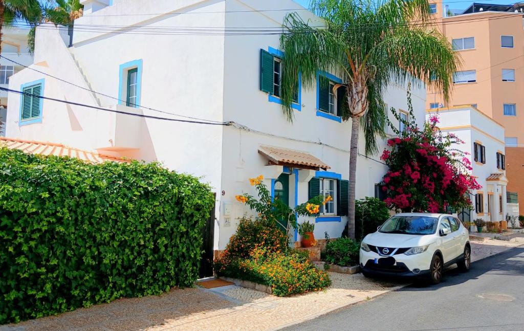 a white car parked next to a house with a palm tree at Casa Rustica - Entire Courtyard House - Sunny Patio in Olhão