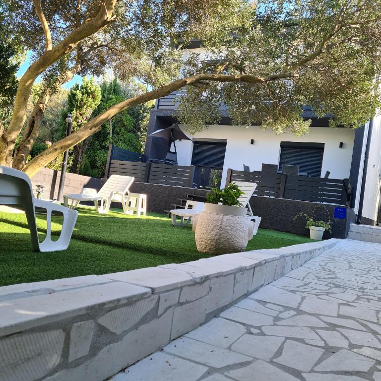 a patio with benches and a yard with grass at Apartmani PARDON in Pag