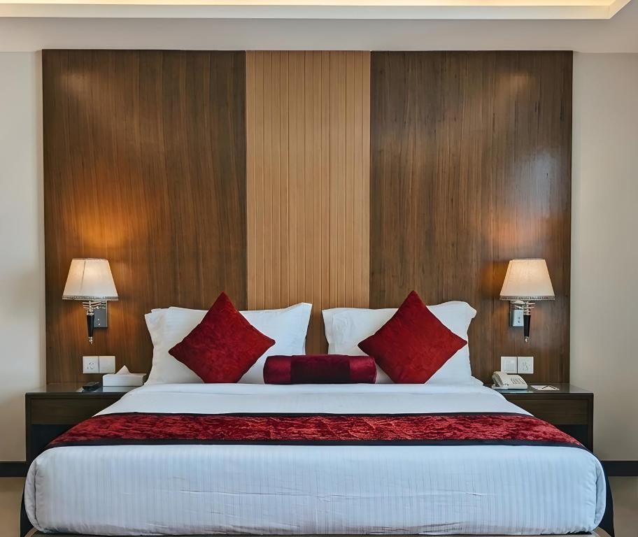 a bedroom with a large bed with red pillows at City Tower Hotel in Fujairah