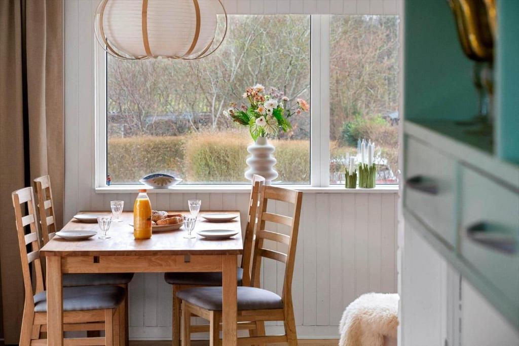 a table with chairs and a vase of flowers on a window at 1671-Vejby-Blommevaenget-2 in Vejby